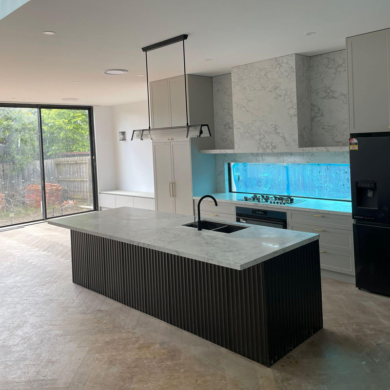 Kitchen island with a grey marble top and black fluted panels