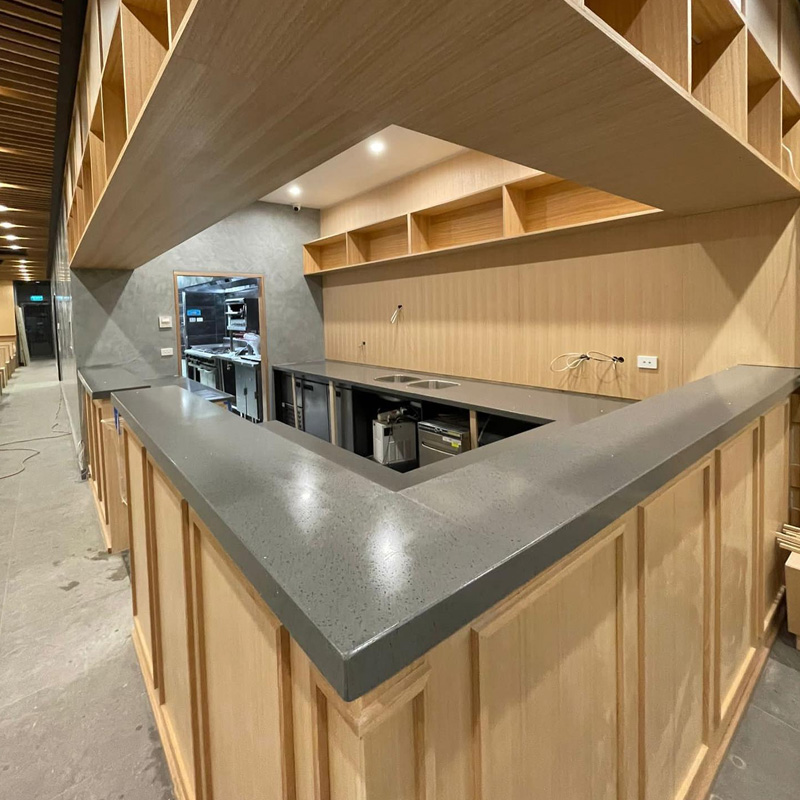 Commercial counter with a grey stone top and timber panelled front