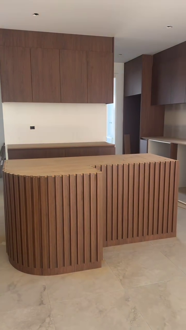 Curved island bench clad in vertical timber battens